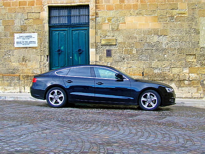 blue sedan parked on concrete pavement near brown building during daytime thumbnail
