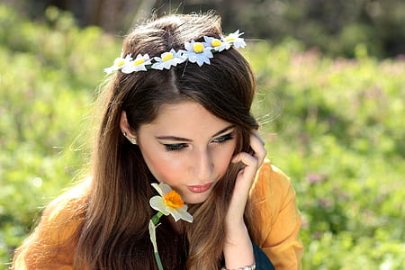 woman holding a white daffodil wearing flower headdress selective-focus photo thumbnail