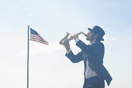 man playing instrument near Flag of America during daytime thumbnail