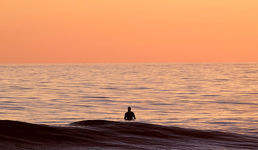 silhouette of man in body of water during daytime thumbnail