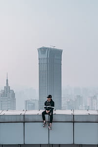 man sitting on top of building wall thumbnail