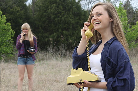 smiling woman holding yellow desk phone thumbnail