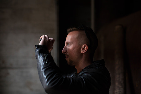 man wearing black leather jacket standing in dark room thumbnail