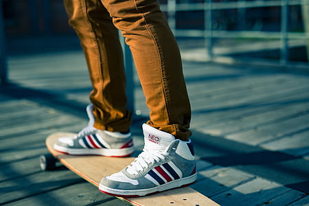 person wearing gray-white-and-red high-top sneakers on beige longboard thumbnail