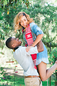 man lifting woman under green leaf tree during daytime thumbnail