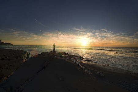 man standing beside cliff near body of water thumbnail