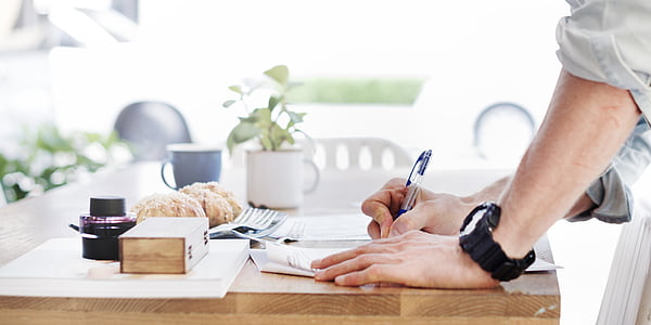 person writing on paper over table thumbnail