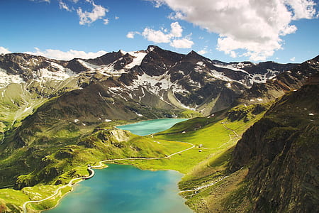aerial landscape photo of green mountain range near blue lake under cloudy sky during daytime thumbnail