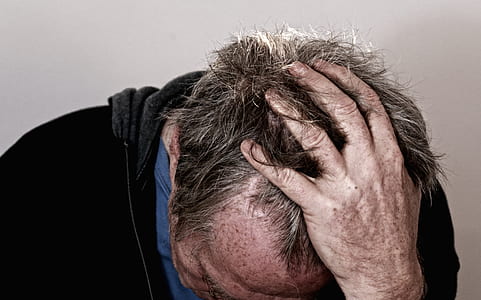 man in black shirt holding head looking down thumbnail