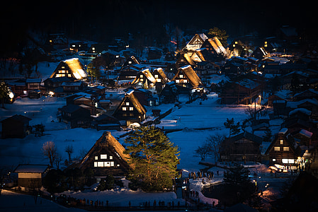 snow covered town with lights during night time thumbnail