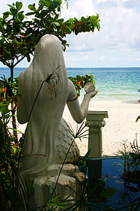 mermaid statuette facing body of water thumbnail