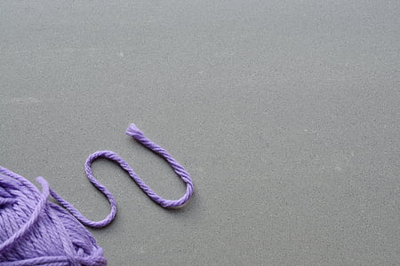 purple yarn on top of gray concrete thumbnail