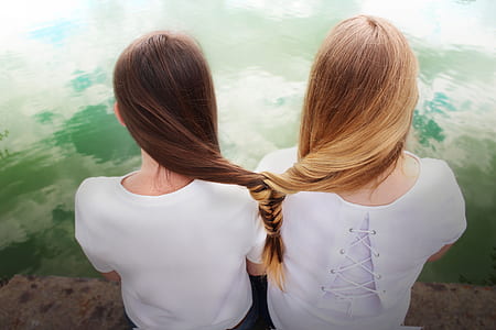 two women sitting near body of water thumbnail