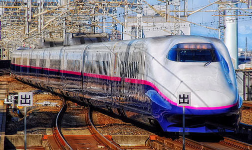 white and blue bullet train on brown trail rails during daytime thumbnail