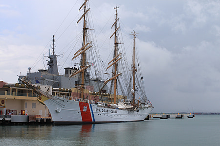 white sail ship docked near brown ship thumbnail