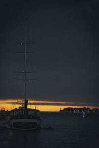 white and black sailboat on water at golden hour thumbnail