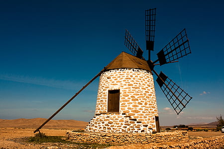 photo of white and brown concrete windmill under blue sky at daytime thumbnail