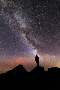 silhouette photography of person standing on rock under milky way thumbnail