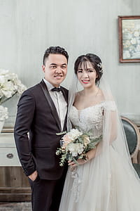 Man Wearing Black Suit Beside Woman Wearing Wedding Dress Standing Inside Room thumbnail