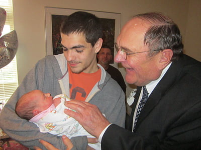two men looking at baby inside room thumbnail