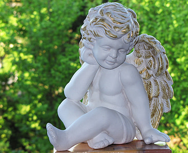 cherub statue near green leafed plants thumbnail