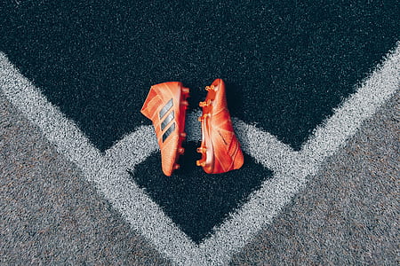 pair of orange adidas soccer cleats on game field thumbnail