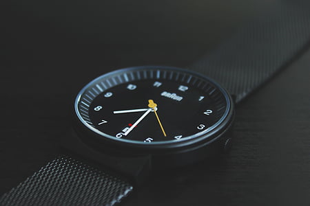 round black analog watch with black band on black surface thumbnail
