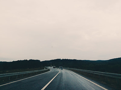 vehicle traveling on a road under dark cloudy sky thumbnail