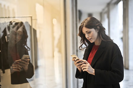 Close-up Photo of Woman in Black Coat Using Smartphone thumbnail