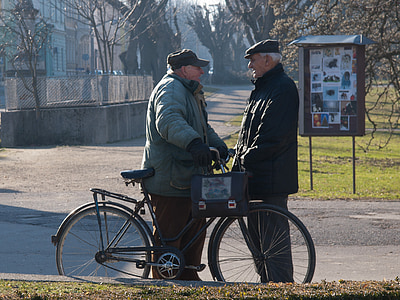 two men talking in front of bicycle on street thumbnail