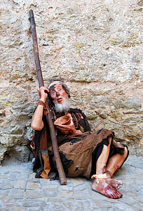 man sitting on ground while leaning on wall thumbnail