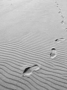 Grayscale Photo of Footprints on Sand thumbnail