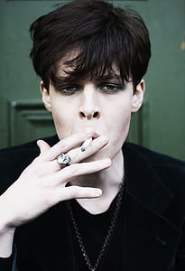 man wearing black shirt while holding cigarette stick thumbnail