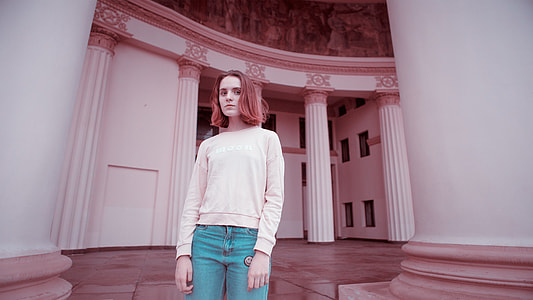 woman wearing beige crew-neck long-sleeved shirt standing beside white concrete stand at daytime thumbnail