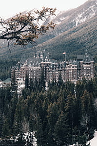 beige wall paint building near trees and mountain during daytime thumbnail