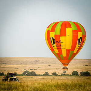 floating hot air balloon near people riding vehicle thumbnail
