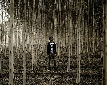 man in black jacket standing near trees thumbnail