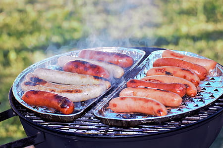 sausages on top of foil on grill on grass at daytime thumbnail