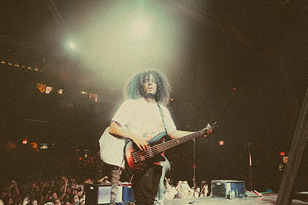 man standing on stage while playing guitar in front of crowd thumbnail