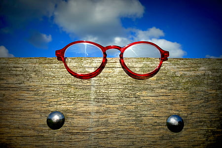 red framed eyeglasses on brown wooden frame thumbnail
