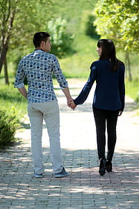 man and woman holding hands walking on road thumbnail
