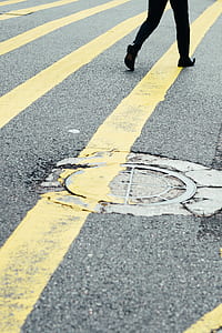 person walking on street with yellow mark during daytime thumbnail