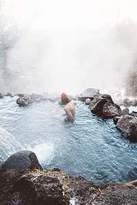man soaking in body of water surrounded with fog thumbnail