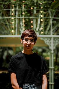 boy wearing black crew-neck t-shirt standing behind green and white building thumbnail