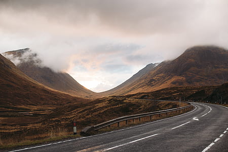 gray concrete road between mountains during daytime thumbnail