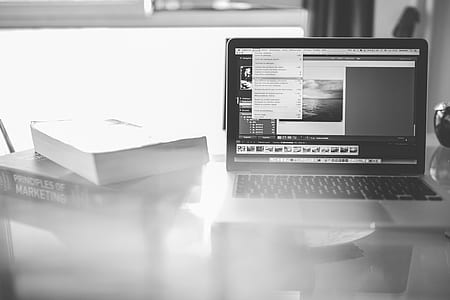 grayscale photo of laptop computer beside two books thumbnail