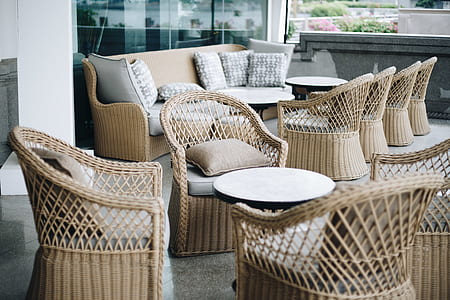 several wicker brown tub chairs around round white metal coffee table thumbnail