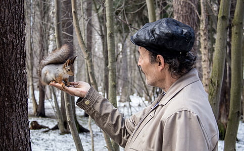 man holding squirrel near tree during daytime thumbnail