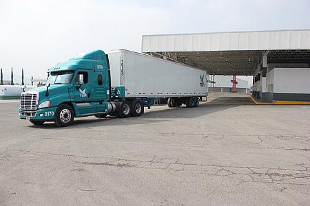 teal and white freight truck near building at daytime thumbnail