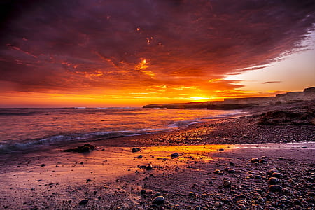 rocks near ocean under sunset thumbnail
